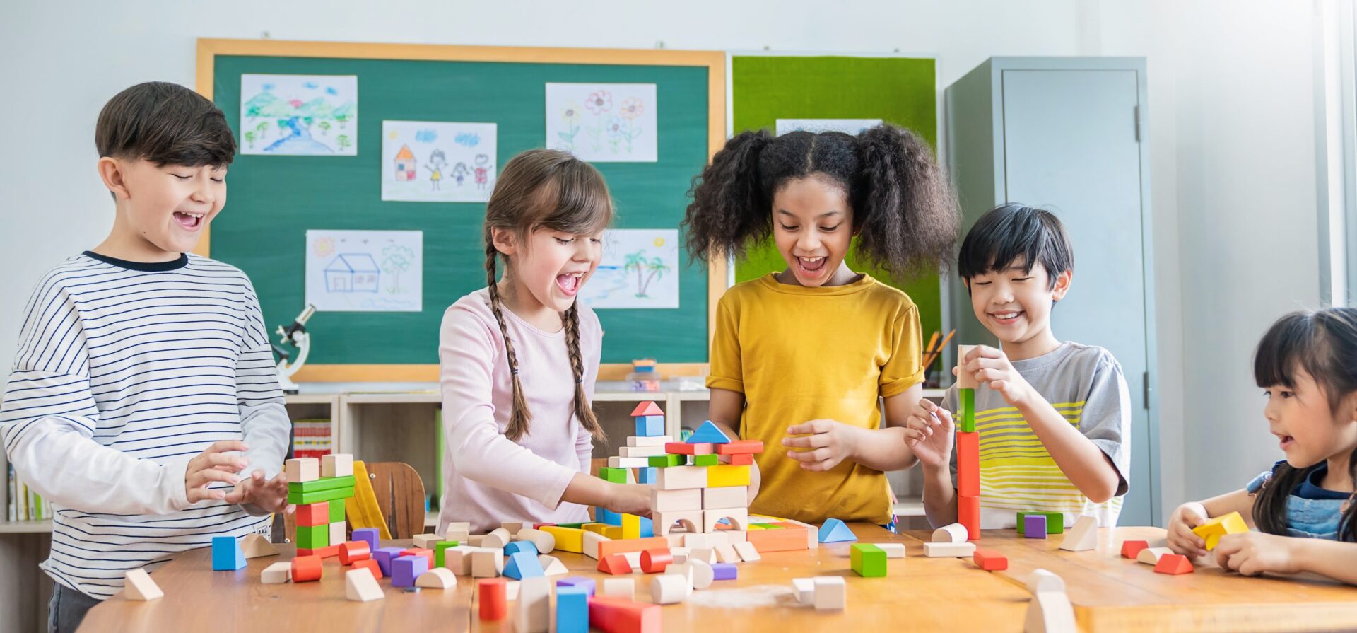 Portrait of asian caucasian little children playing colorful blocks in classroom. Learning by playing education group study concept. International pupils doing activities brain training in primary school.